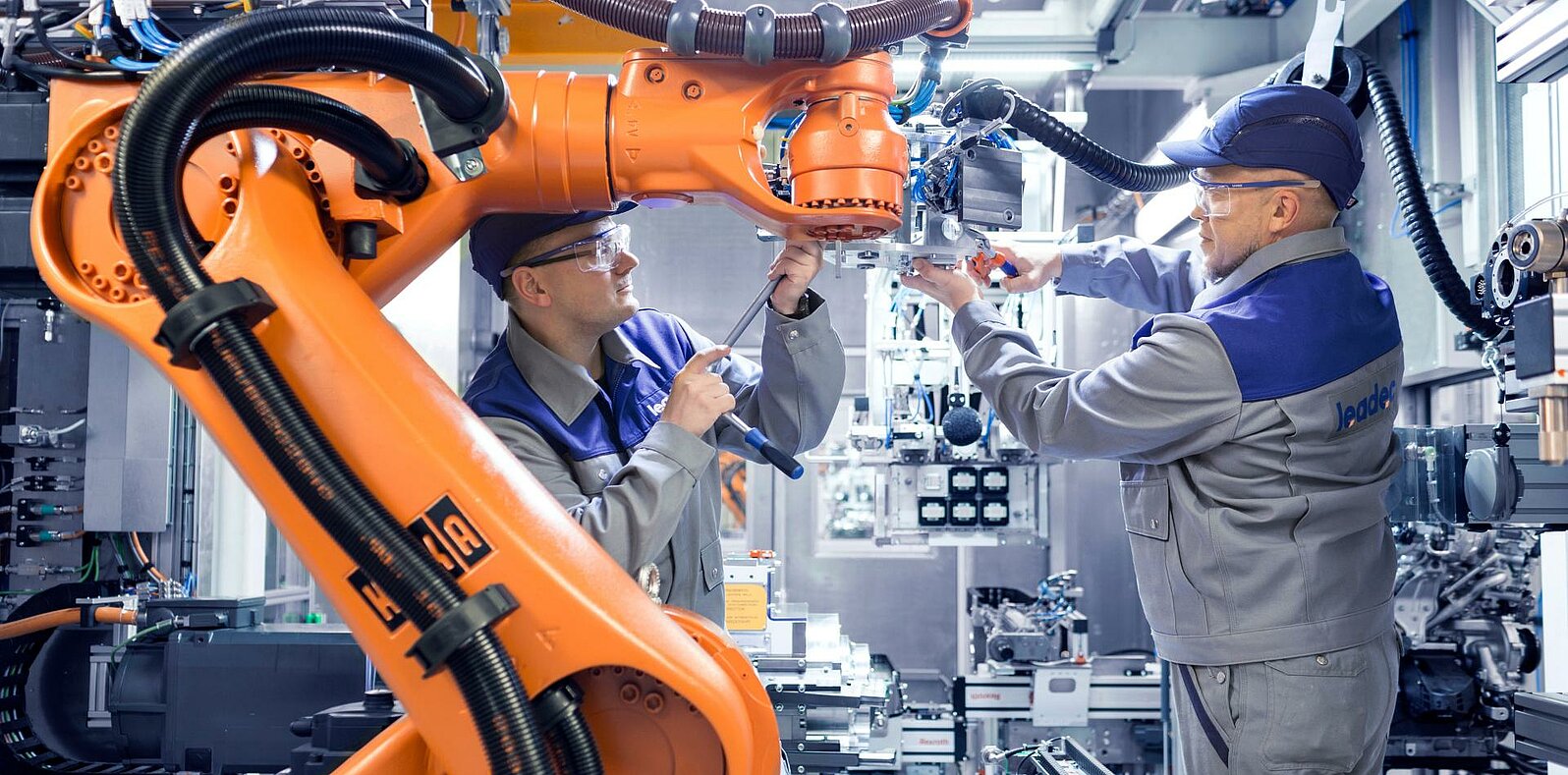 Two Leadec employees maintaining a robot in a production.